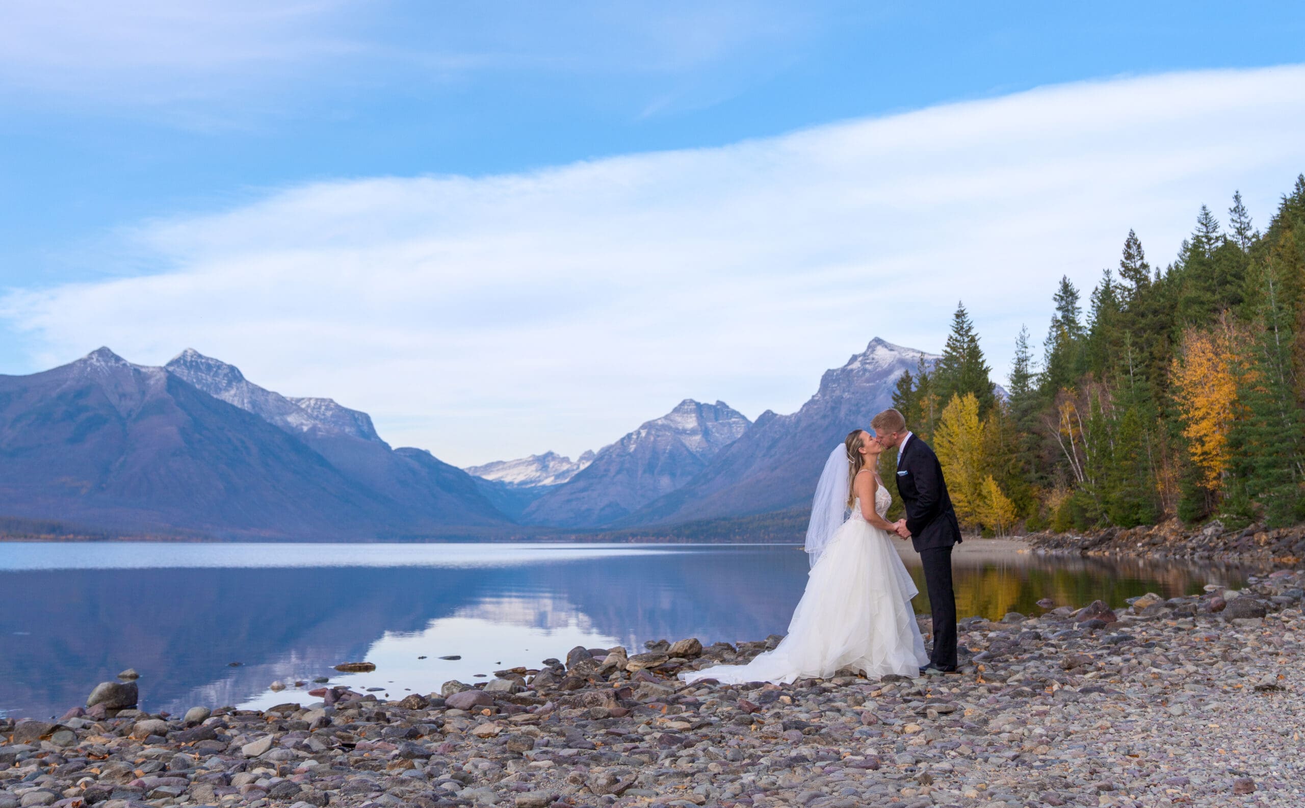 Couple eloping at Glacier National Park with mountain and lake backdrop, photographed by Joseph Mayden Photography