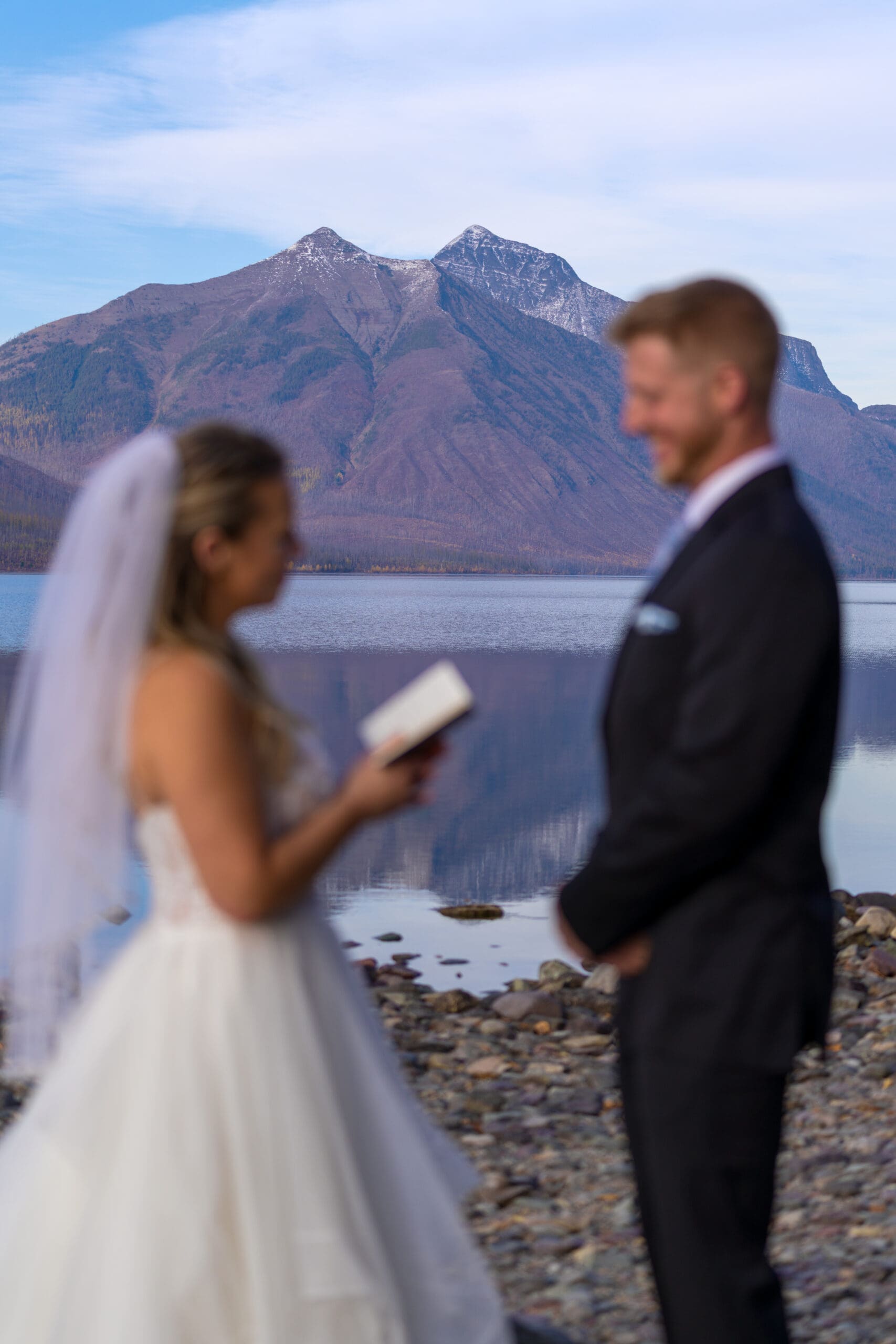 Couple at Lake McDonald Glacier National Park elopement ceremony with colorful rocks and mountain reflections
